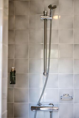 a shower head in a bathroom with white tiles at Hotel Kasteel Hoekelum in Bennekom