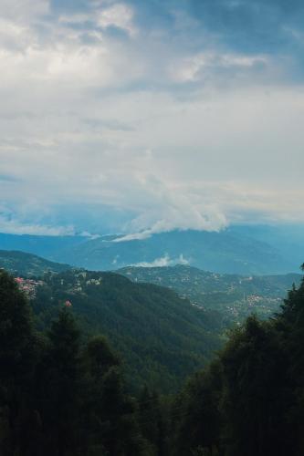 a view of a city from a hill with trees at The Heaven Resort, Dalhousie - A Beautiful Wellness Resort in the Lap of Nature in Dalhousie