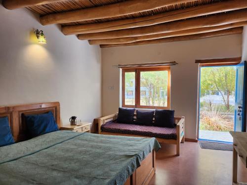 a bedroom with a bed and a couch and a window at Lharimo North Cottages - Nubra Valley in Wāhegaon