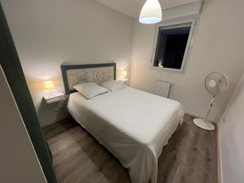 a bedroom with a white bed and a fan at Le Parc! T3 climatisé, Parking, Piscine in Carcassonne