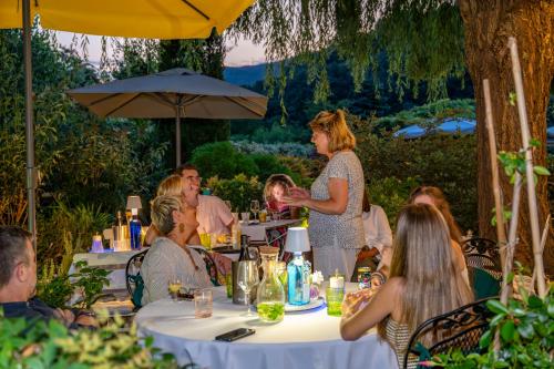 a group of people sitting at tables in a garden at Villa Valentina in Levanto