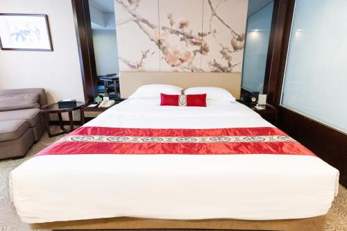 a bedroom with a large white bed with red pillows at Guangdong Yingbin Hotel-Free Canton Fair Shuttle Bus in Guangzhou