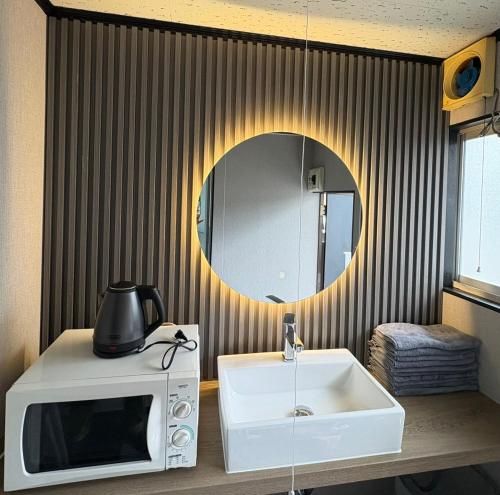 a bathroom with a microwave and a mirror at 若葉コーポ103 in Fukuoka
