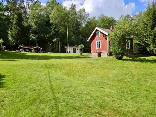 a large yard with a red house in the background at Sommarstuga i Björneröd Strömstad, Mitt i naturen! in Strömstad