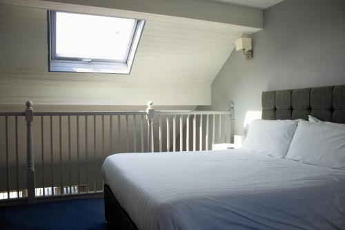 a bedroom with a bed with a window above it at Littleover Lodge Hotel in Derby