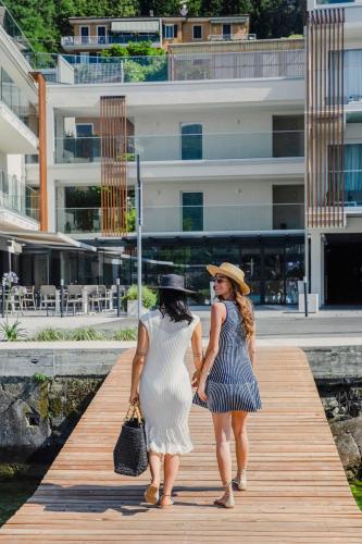 two women are walking on a wooden boardwalk at Ah Porticcioli Boutique Apartments in San Felice del Benaco