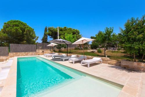 a swimming pool with lounge chairs and umbrellas at Villa Petricore by Perle di Puglia in Marina di Pescoluse