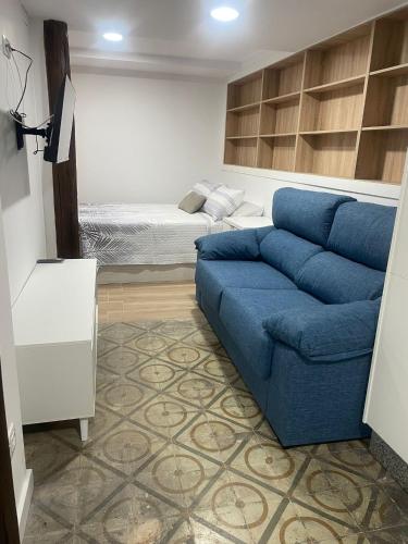a living room with a blue couch and a bed at CASA CRISTINA Alojamiento céntrico en pleno casco histórico y centro de la ciudad in Monforte de Lemos