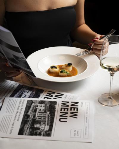 a woman sitting at a table with a plate of food at Ah Porticcioli Boutique Apartments in San Felice del Benaco