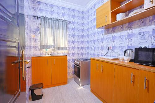 a kitchen with orange cabinets and a blue and white wallpaper at Victoria Flats in Ijegun