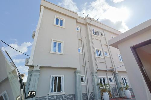 a white building with blue windows and plants at Victoria Flats in Ijegun