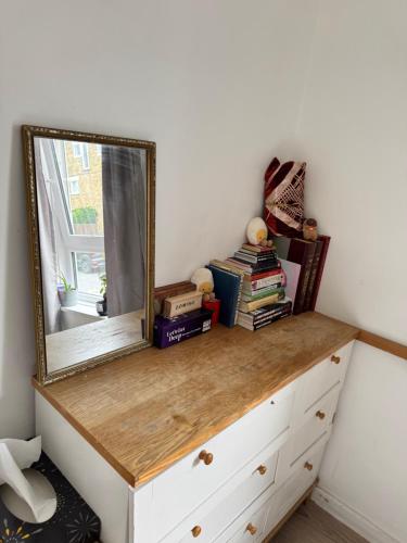 a mirror on top of a dresser with books at Sunset View 2BR Apartment - Beautiful London View & Free Parking in London