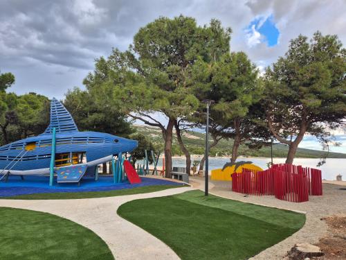 a playground with a blue boat and a slide at Mobilna kućica Val in Šimuni