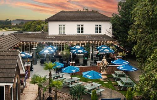a building with blue tables and blue umbrellas at Littleover Lodge Hotel in Derby