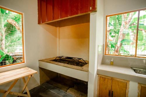 a kitchen with a stove and two windows at Loboc Nature View House in Loboc
