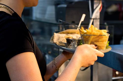 a person holding a bowl of fries and a plate of food at Littleover Lodge Hotel in Derby
