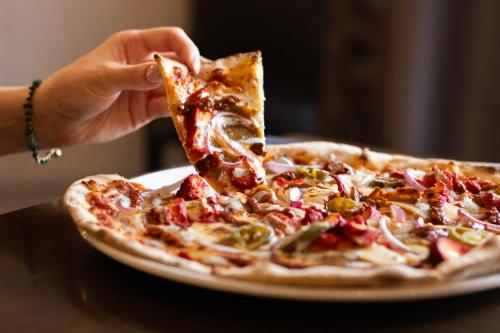 a person eating a slice of pizza on a plate at Littleover Lodge Hotel in Derby