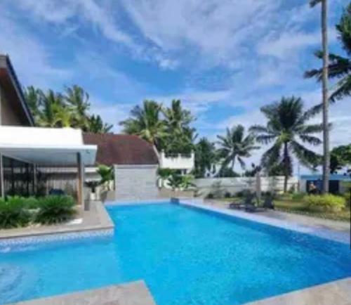 una gran piscina de agua azul frente a una casa en Cebu beachfront house, 