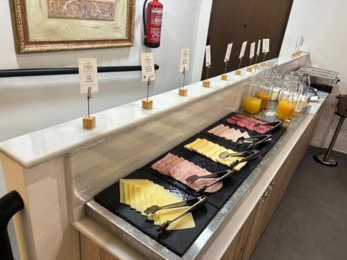 Hotel Europa Boutique Sevilla في إشبيلية: طابور بوفيه مع اللحوم والجبن والمشروبات