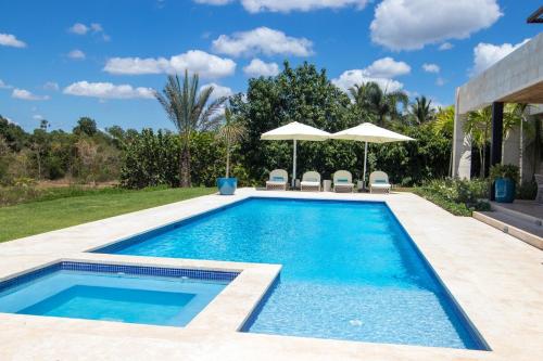 a swimming pool in a backyard with umbrellas at Villa Libertad, amazing pool ,modern design in El Infiernito