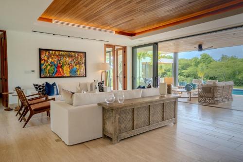 a living room with white furniture and a painting on the wall at Villa Libertad, amazing pool ,modern design in El Infiernito