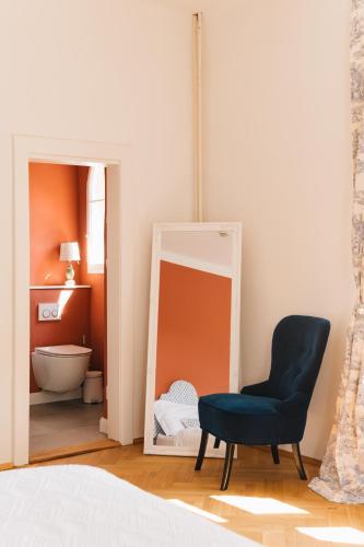 a bedroom with a blue chair and a mirror at Zámecká Stodola - Červený Hrádek u Sedlčan in Sedlčany