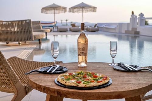 a table with a pizza and a bottle of wine at Paolas Sunset in Agios Stefanos