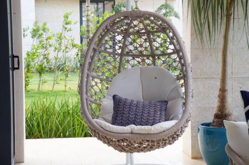 a wicker chair with a blue pillow in a porch at Villa Libertad, amazing pool ,modern design in El Infiernito
