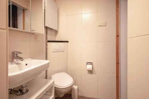 a white bathroom with a sink and a toilet at Aangenaam Texel Familie Bungalow in De Koog