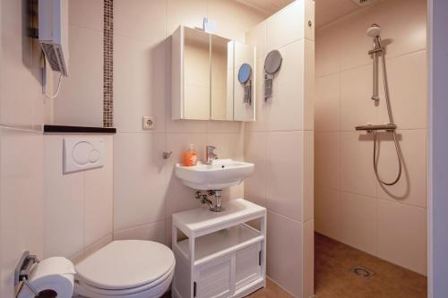a white bathroom with a toilet and a sink at Aangenaam Texel Familie Bungalow in De Koog