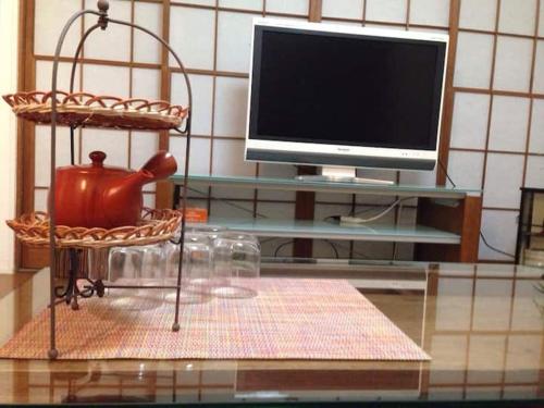 a glass table with a television and a tea kettle on a chair at 西新宿和庵 wa-an homestay in Tokyo