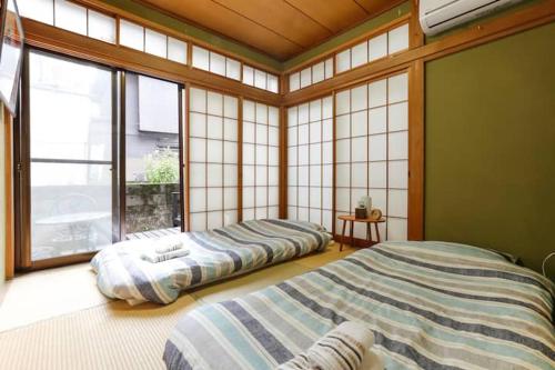 two beds sitting in a room with windows at 西新宿和庵 wa-an homestay in Tokyo