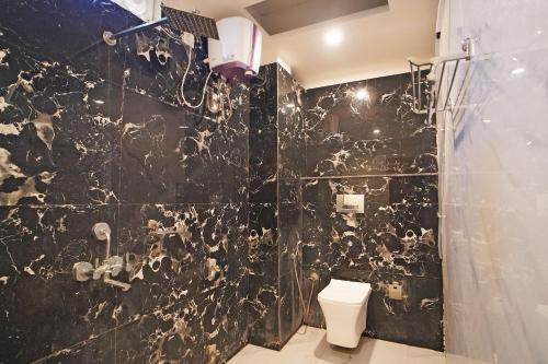 a black tiled bathroom with a toilet and a shower at Holiday Beach Resort !! Beach Distance 50 Mts !! in Mandarmoni