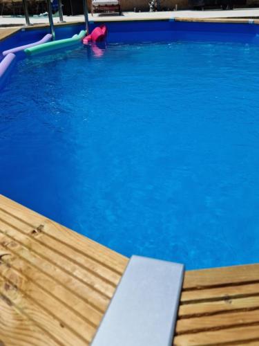 a swimming pool with blue water and a raft at Bohème glamping expérience in Berson