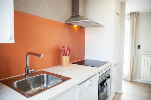a kitchen with a sink and an orange wall at Zabella Ossau - Nuevo ático a estrenar en el tubo in Zaragoza