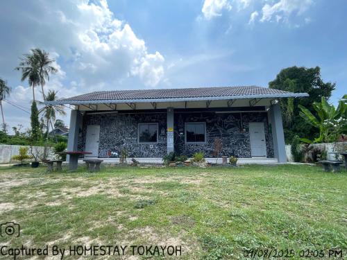a small house with a grass yard at Homestay Studio TOKAYOH in Kota Bharu