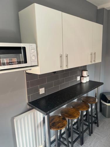 a kitchen with a counter with stools and a microwave at Affordable Luxury 4 Stunning apartment Sunderland close to City centre hospital Crown Works Studio and Nissan in Sunderland