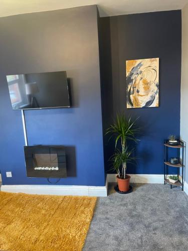 a living room with a blue wall with a flat screen tv at Affordable Luxury 4 Stunning apartment Sunderland close to City centre hospital Crown Works Studio and Nissan in Sunderland