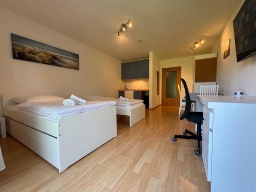 a room with two beds and a desk and a chair at WuP Living Apartment am Stadtwald TG Parkplatz in Augsburg