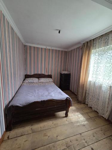 a bedroom with a bed with striped walls and a window at Chvibiani Guesthouse & Bar in Ushguli