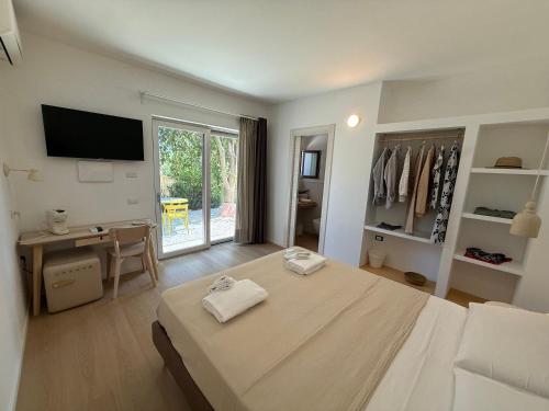 a bedroom with a bed and a desk and a television at Mariposa Rooms in San Teodoro