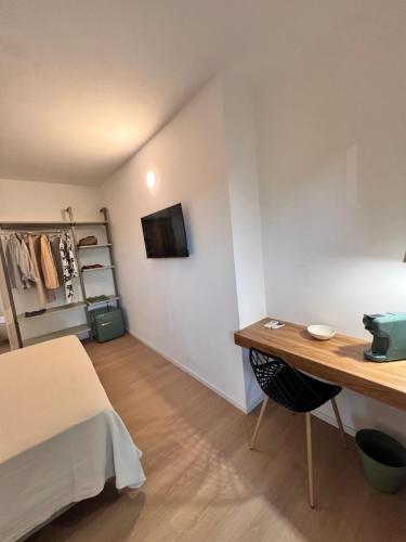 a room with a bed and a desk and a television at Mariposa Rooms in San Teodoro