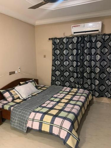 a bedroom with a bed with a blanket and a wall at StayComidad in Dawhwenya