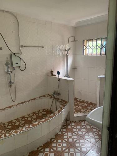a bathroom with a tub and a shower and a sink at StayComidad in Dawhwenya