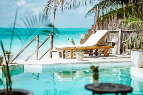 a resort pool with a chaise lounge and the ocean at ZAN Tropical Island in Bwejuu
