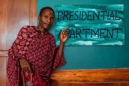 a man sitting on a bench in front of a sign at ZAN Tropical Island in Bwejuu