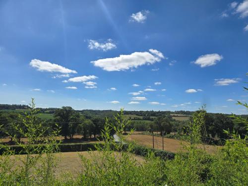 a blue sky with clouds over a field and trees at Les chambres de la Vallée Cachée in Callac