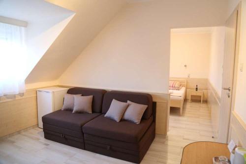 a living room with a brown couch with two pillows at Péterfia Panzió in Debrecen