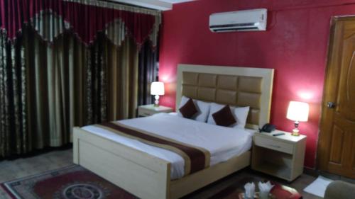 a bedroom with a large bed with red walls at Premier Inn Heights hotel Davis Road Lahore in Lahore