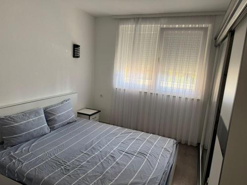 a small bedroom with a bed and a window at Fb apartments 2 in Gjilan